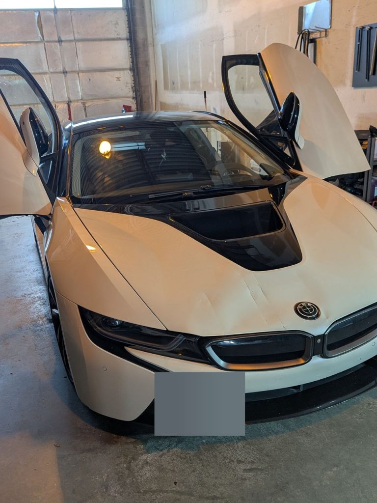 Creases across the hood and nose of a white BMW i8 before paintless dent repair