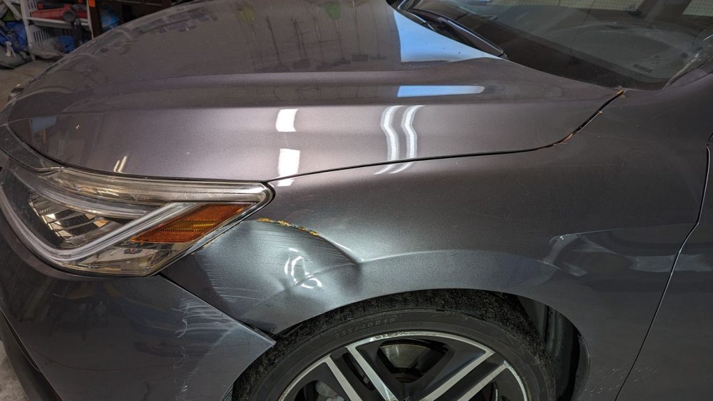 Creased front fender on a grey Honda Accord before repair