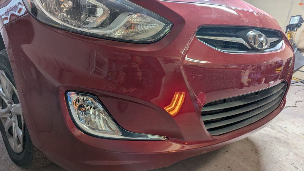 Red Hyundai Accent front bumper after body repair and paint