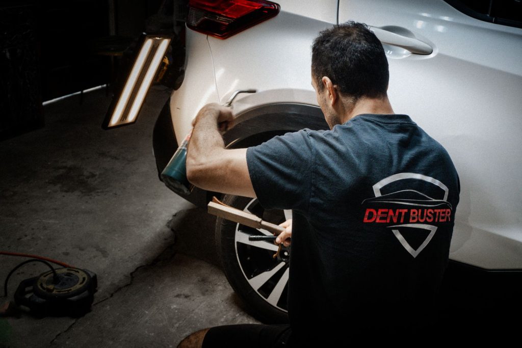 Repairing a white SUV under a PDR light board