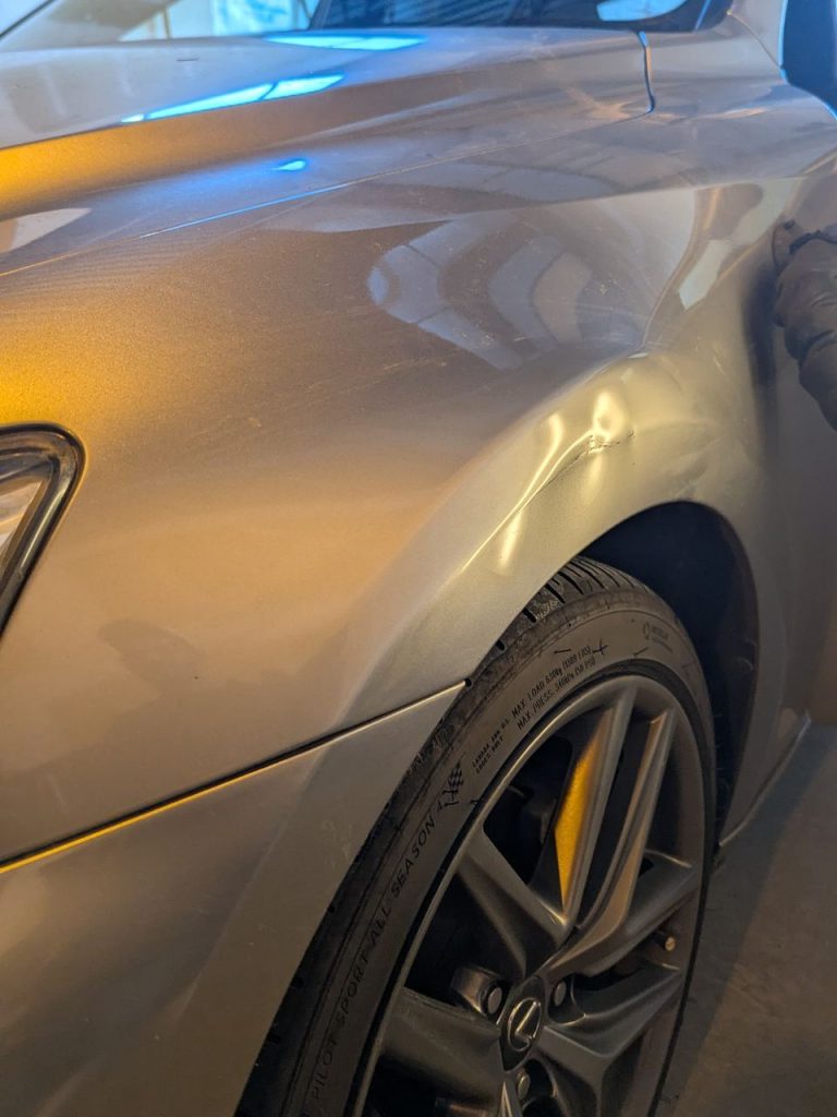 Front fender dent on a grey sedan before paintless dent repair