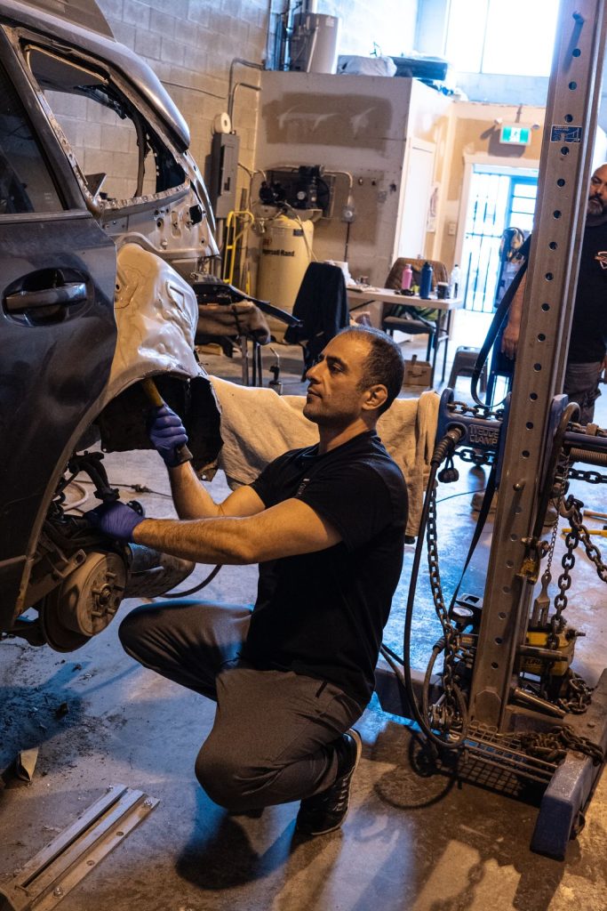 Technician straightening a rear wheel arch in the Dent Buster shop