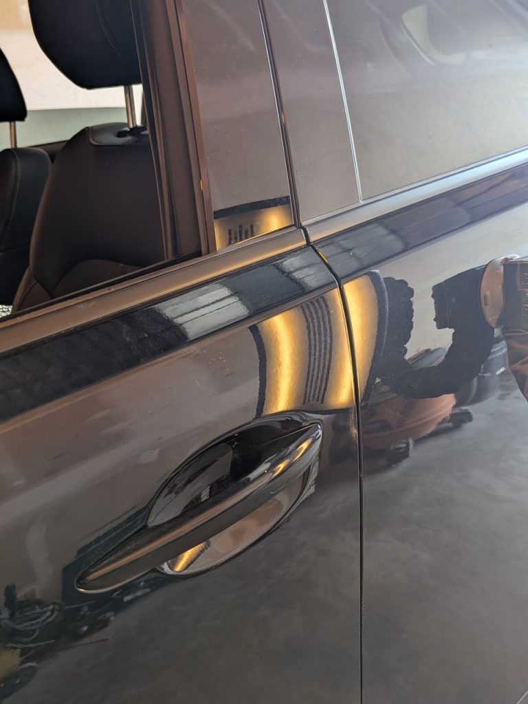 Dark SUV door after paintless dent repair, reflection lines straight