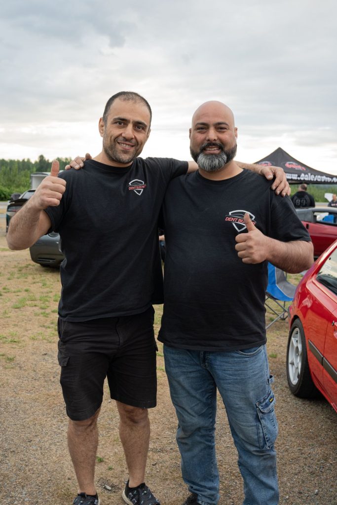 Two Dent Buster technicians giving a thumbs up at a car show